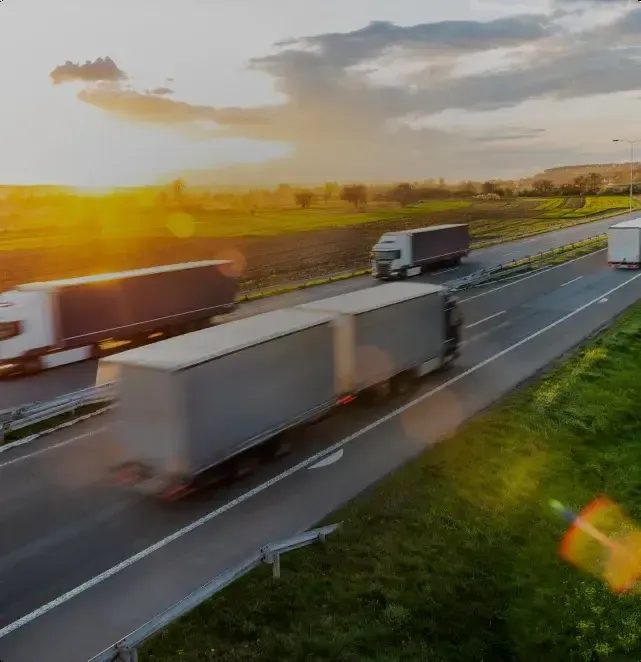 Freight trucks on a motorway at golden hour, representing WibiCharge's commercial vehicle pilot